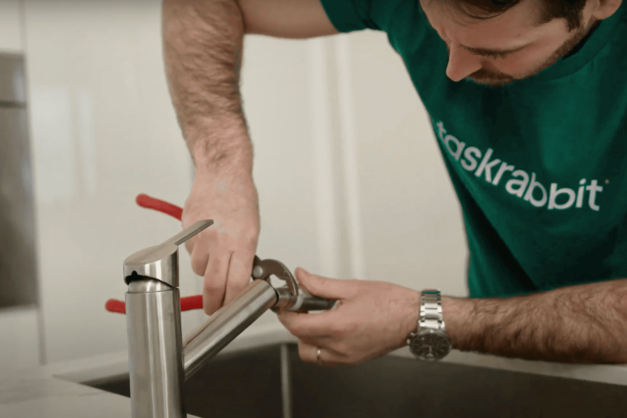 une personne qui utilise une clé à molette pour serrer un tuyau d'évacuation sous un évier.