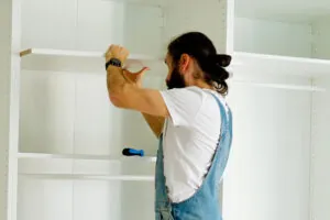 homme installant une étagère dans une penderie