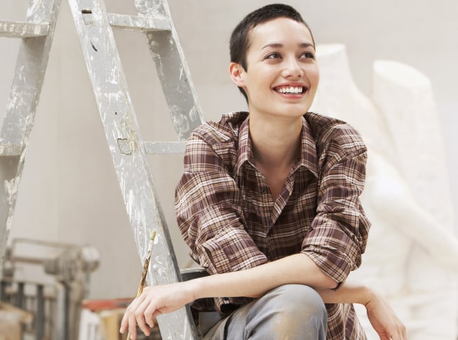 Personne assise sur une échelle après avoir effectué de la peinture